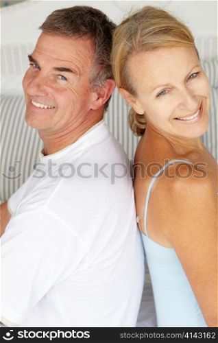 Happy couple sitting back to back on bed