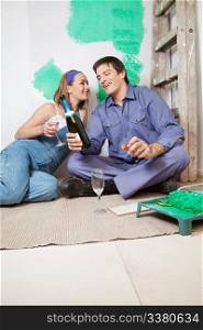 Happy couple sitting on floor and having champagne