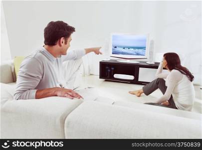 happy couple sitting on sofa and watching television together