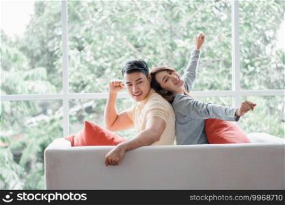 Happy couple sitting on the sofa and being a man teases his girlfriend with love in the living room and relax. Concept of romantic on valentine day. Proposal and marriage