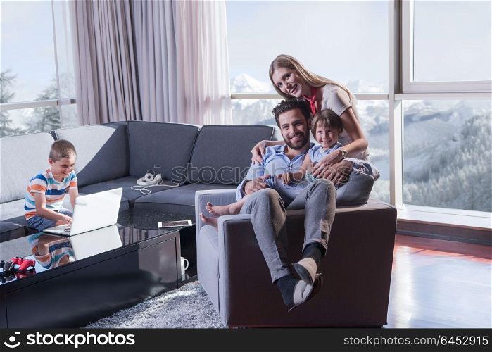 happy couple spending time with kids using tablet computer on an armchair at home