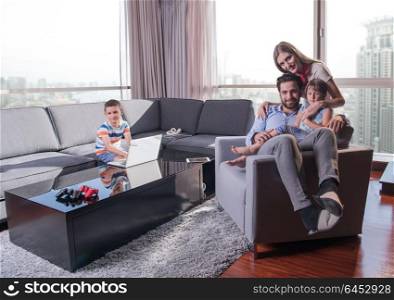 happy couple spending time with kids using tablet computer on an armchair at home