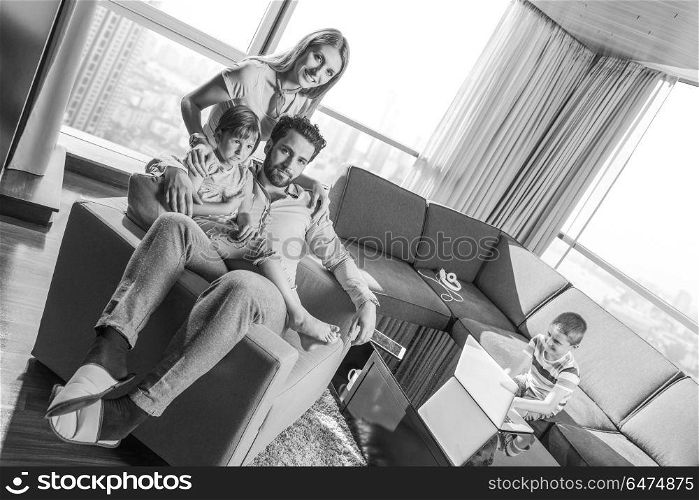 happy couple spending time with kids using tablet computer on an armchair at home. happy young couple spending time with kids