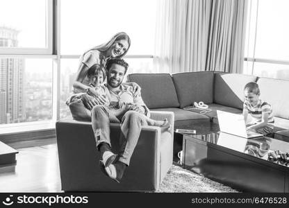 happy couple spending time with kids using tablet computer on an armchair at home. happy young couple spending time with kids