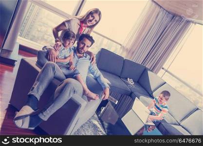 happy couple spending time with kids using tablet computer on an armchair at home. happy young couple spending time with kids