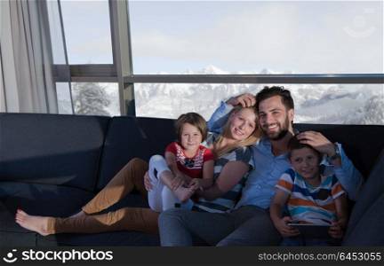 happy couple spending time with kids using tablet computer on sofa at home