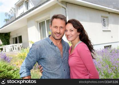Happy couple standing in front of new home
