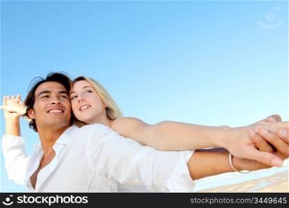 Happy couple stretching arms at the beach