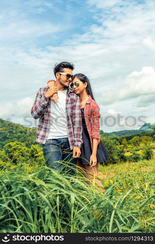 Happy couple take a romantic walk in green grass field on the hills. Travel and honeymoon concept.