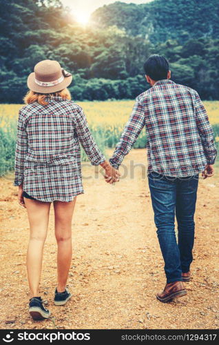 Happy couple take a romantic walk in green grass field on the hills. Travel and honeymoon concept.