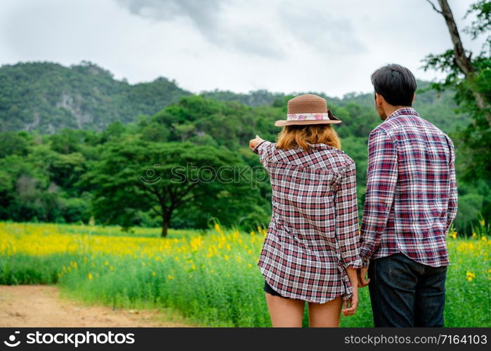 Happy couple take a romantic walk in green grass field on the hills. Travel and honeymoon concept.