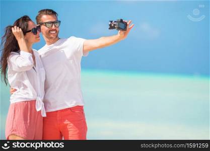 Happy couple taking a selfie photo on white beach. Two adults enjoying their vacation on tropical exotic beach. Happy couple taking a photo on white beach on honeymoon holiday