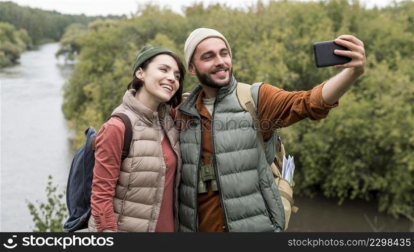 happy couple taking selfie with smartphone nature