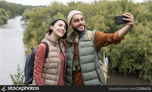 happy couple taking selfie with smartphone nature