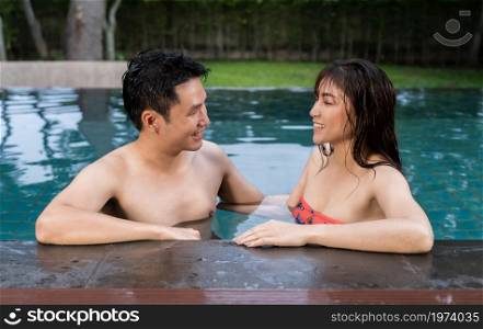 happy couple talking at the edge of swimming pool