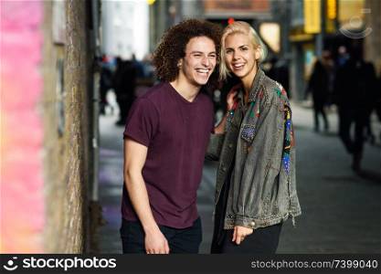 Happy couple talking in urban background on a typical London street.. Young couple talking in urban background on a typical London street.