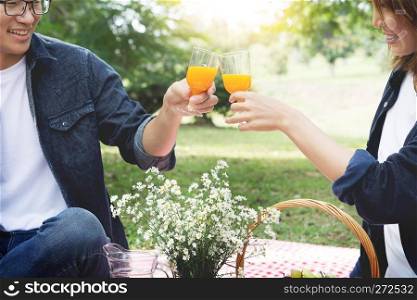 Happy couple toasting wineglasses while sitting on picnic blanket, summer, holidays, vacation, music, happy people concept 