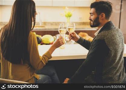 Happy couple toasting with white wine in the modern kitchen