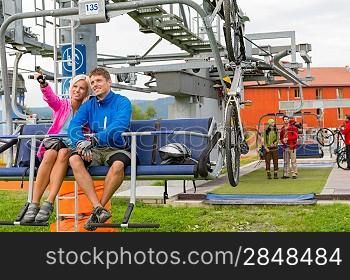 Happy couple traveling by chair lift enjoying landscape