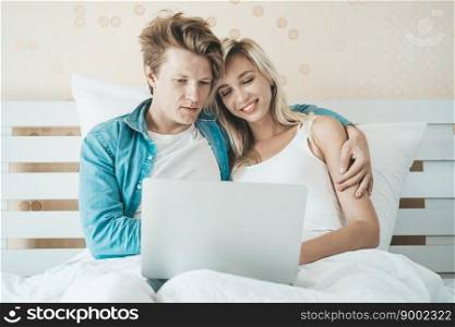 Happy couple Using laptop computer on the bed