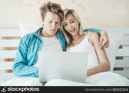 Happy couple Using laptop computer on the bed