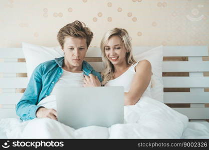 Happy couple Using laptop computer on the bed