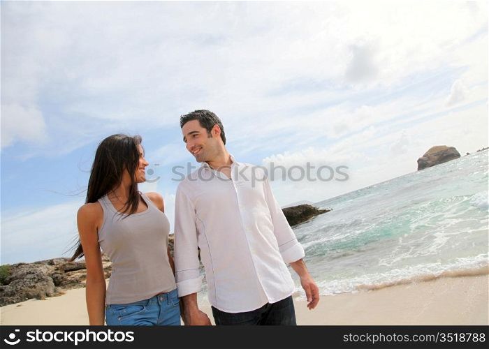 Happy couple walking by caribbean beach