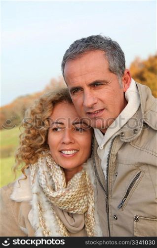 Happy couple walking in country field in autumn