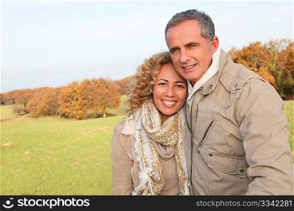 Happy couple walking in country field in autumn