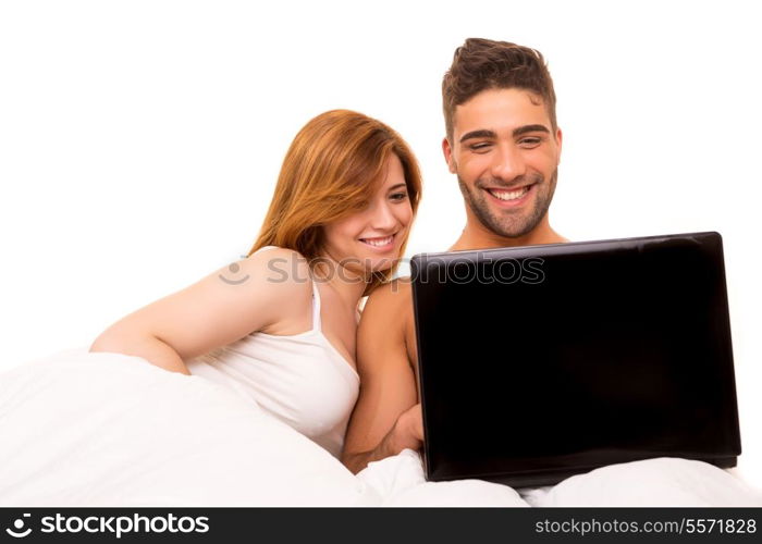 Happy couple watching a movie in bed