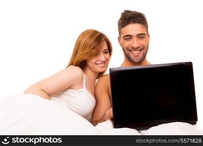 Happy couple watching a movie in bed