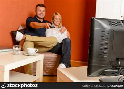 Happy couple watching tv evening relaxing changing channels remote control