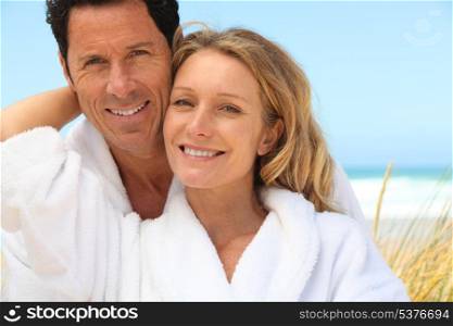 Happy couple wearing dressing gowns at the beach