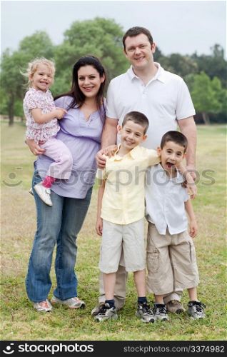 Happy couple with divine kids looking at you at the park