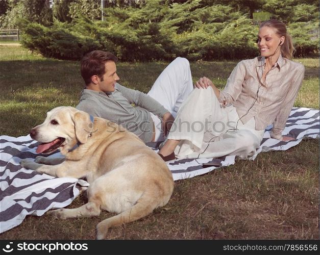 happy couple with dog, lovers listen to music in park