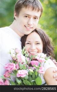 Happy couple with flowers against green spring background