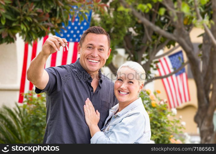 Happy Couple With New House Keys In Front of Houses with American Flags.