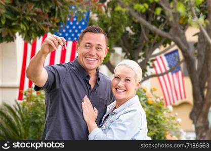 Happy Couple With New House Keys In Front of Houses with American Flags.