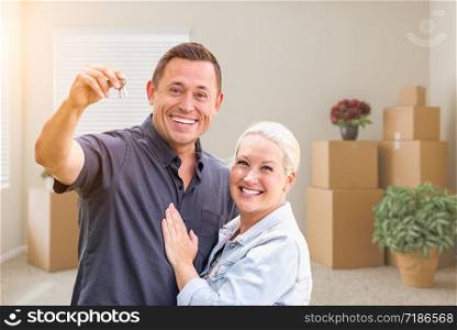 Happy Couple With New House Keys Inside Empty Room with Boxes.