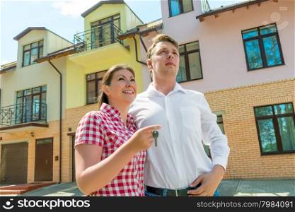 happy couple with the keys in the hands about his new townhouse