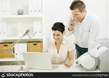 Happy couple working at home using laptop computer, smiling.