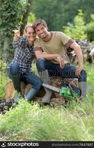 happy couple working with a chainsaw in the forest