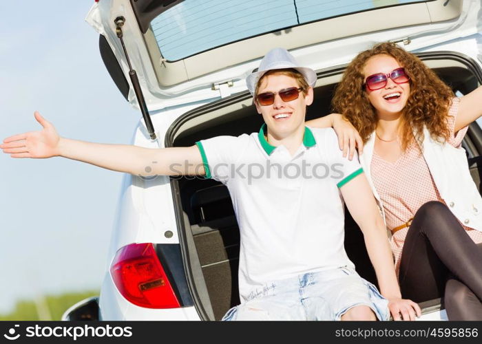 Happy couple. Young happy couple sitting in car trunk outdoor