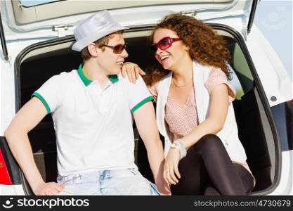 Happy couple. Young happy couple sitting in car trunk outdoor