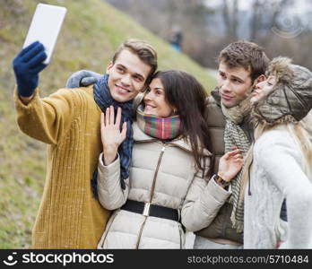 Happy couples taking self portrait through cell phone in park