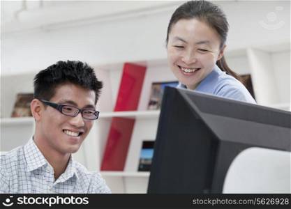 Happy coworkers working on their computer in the office