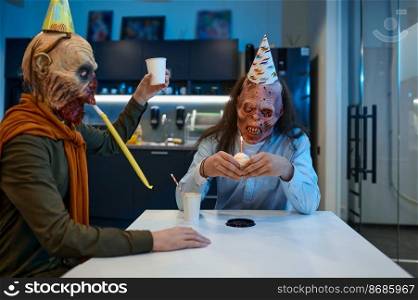 Happy creepy zombie employees in festive cap congratulating his colleague with birthday party during lunch time in office. Zombie employees congratulate colleague with birthday