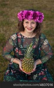 Happy curvy girl with a pineapple and a flower crown in the landscape
