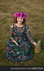 Happy curvy girl with a pineapple and a flower crown in the landscape