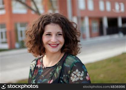 Happy curvy girl with curly hair in the street with a flowered dress